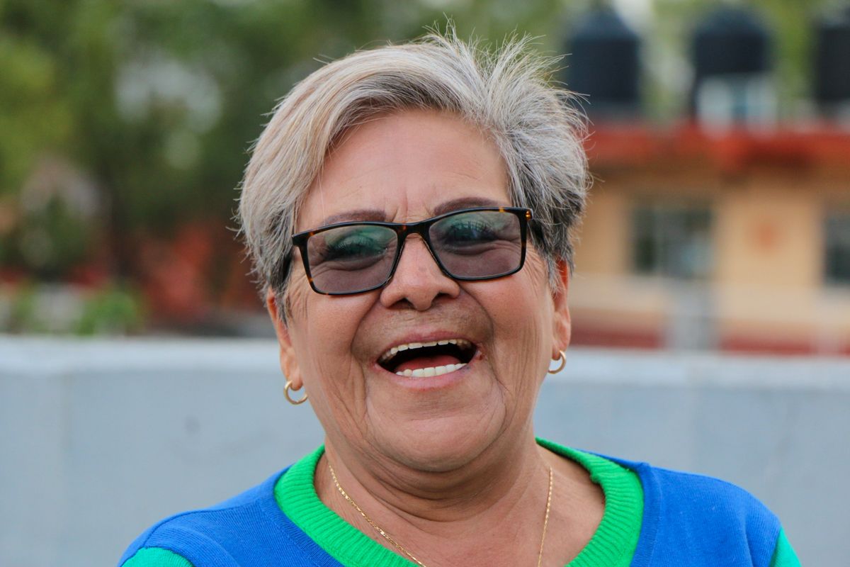 An elderly woman smiling and laughing outdoors